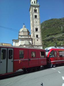 um comboio vermelho estacionado em frente a uma torre do relógio em A Casa Di Nonna em Tirano