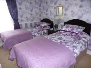 two beds in a bedroom with purple wallpaper at Hillside Bed and Breakfast in Bedale