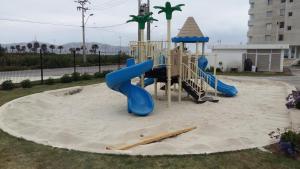 een speeltuin met een blauwe glijbaan in het zand bij Departamento con vista al mar in Coquimbo