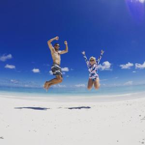 Ein Mann und eine Frau springen in die Luft am Strand in der Unterkunft Salt Beach Hotel in Maafushi