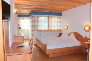 a bedroom with a bed and a desk and a television at Pension Widmann in Stulles