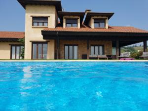 a villa with a swimming pool in front of a house at La Casa de Orviz in Siero