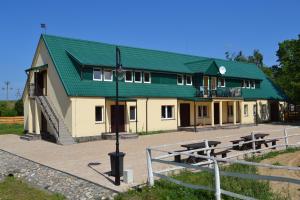 a building with a green roof with benches in front at Rancho Ulinia koło Łeby in Ulinia