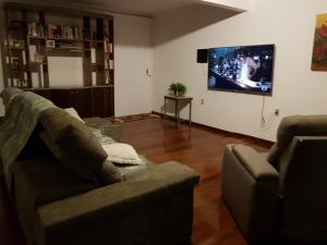 uma sala de estar com um sofá e uma televisão de ecrã plano em Casa da Lúcia em Uberlândia