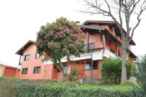 an orange building with a flowering tree in front of it at Pousada Monte Carlo in São Joaquim
