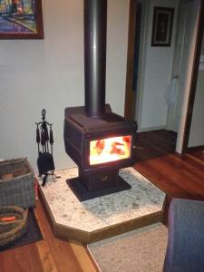 a fireplace in a living room with a stove at Kookaburra Cottage at Uralba Eco Cottages in Upper Horseshoe Creek