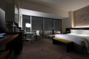 a hotel room with a bed and a desk with a view at Osaka Marriott Miyako Hotel in Osaka
