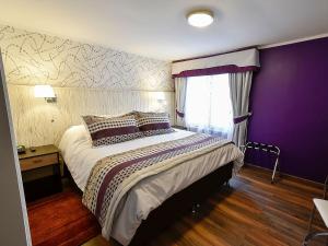 1 dormitorio con 1 cama grande y pared morada en LV Hoteles Boutique, en Viña del Mar