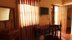 Habitación con cortina, mesa y TV. en Inti Sayana en Humahuaca