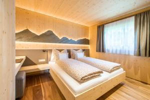 a bedroom with two beds and a large window at Mair am Graben Farm * Chalets in Terento