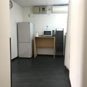 a kitchen with a refrigerator and a desk with a microwave at Lucky Hostel in Tokyo