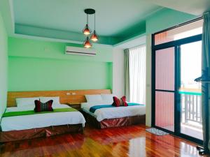 two beds in a room with green walls at 198紅帽民宿l市區l電梯l停車場 in Magong