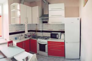 een keuken met rode kasten en een witte koelkast bij Lucky Apartment - Lviv Old Town in Lviv