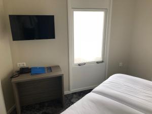 a bedroom with a bed and a desk and a window at Fletcher Hotel - Resort Spaarnwoude in Velsen-Zuid