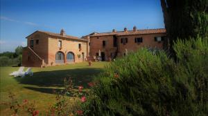 ein großes Backsteingebäude auf einem Feld mit einem Hof in der Unterkunft Agriturismo La Grotta Di Montecchino in Siena