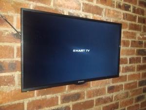 Elle comprend une télévision à écran plat suspendue au mur de briques. dans l'établissement Limonite GuestHouse, à Pretoria