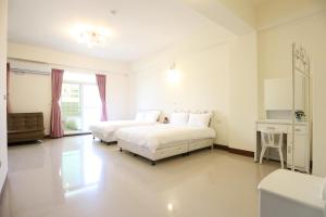 a white bedroom with two beds and a desk at Nice Comfortable Homestay in Taitung City