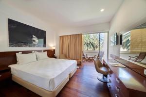 a hotel room with a bed and a desk and a dining room at Hotel Porto Santo & Spa in Porto Santo