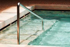 a swimming pool with a metal railing in the water at Hotel Porto Santo & Spa in Porto Santo