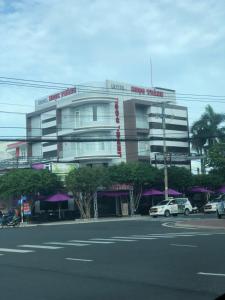迪石的住宿－Ngoc Thanh Hotel，街道上的一座建筑,前面有汽车停放