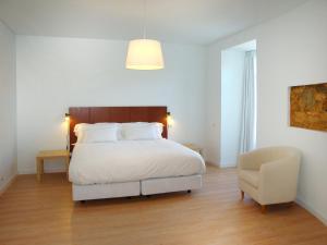 リスボンにあるマイ プレイス リスボン ラウンジ スイーツのベッドルーム(白いベッド1台、椅子付)