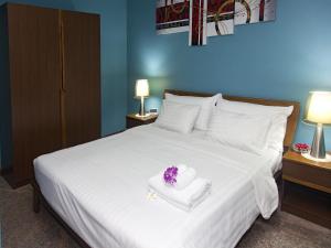 a hotel room with a white bed with a bouquet of flowers on it at Pattaya Garden Apartments Boutique Hotel in Pattaya South +26 photos