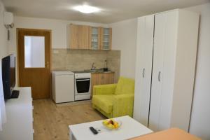 een woonkamer met een gele bank en een keuken bij Apartman Hrupjela in Trebinje
