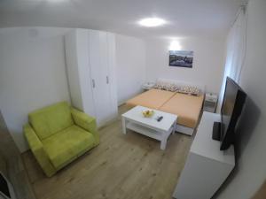 een kleine kamer met een bed en een groene stoel bij Apartman Hrupjela in Trebinje