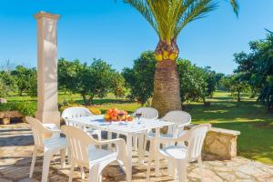 a white table with white chairs and a palm tree at Can Rafelino in Llubí