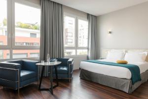 una camera d'albergo con letto, tavolo e sedie di Hotel Atrium by Happyculture a Suresnes