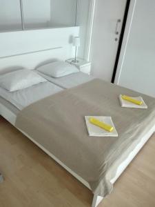 Una cama blanca con dos servilletas y dos utensilios amarillos. en Loft with terrace 24m2, swimming pool and garage en Chirivella