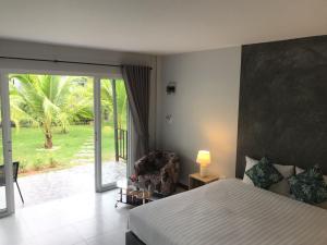 a bedroom with a bed and a chair and a window at Marisa Garden Bungalow in Bang Tao Beach