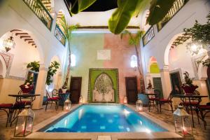 a swimming pool in a building with tables and chairs at Riad Caesar in Marrakesh