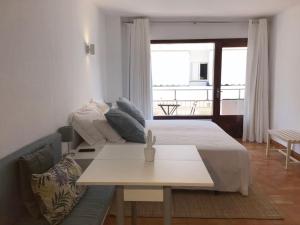 ein Schlafzimmer mit einem Bett, einem Tisch und einem Sofa in der Unterkunft Apartamentos Albertos in Santa Eulària des Riu