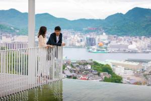 a woman and a man looking out a window at the water at Garden Terrace Nagasaki Hotel & Resort in Nagasaki