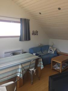 a living room with a blue couch and a table at Villa Penfret - 50 meters from the beach in Île-Tudy