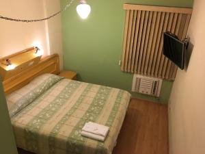 um pequeno quarto com uma cama e uma televisão em Hotel San Marco em São José dos Campos