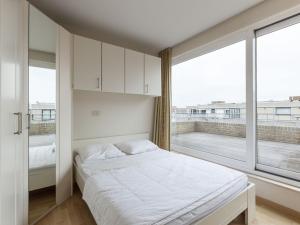 a bedroom with a bed and a large window at Penthouse with 2 terraces and sea casino views in Middelkerke