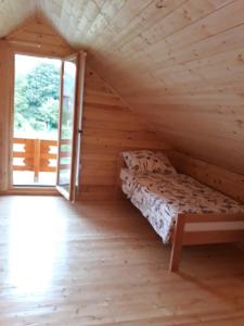 ein Bett in einem Holzzimmer mit Fenster in der Unterkunft Una SI in Lohovo