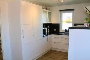 eine Küche mit weißen Schränken und einem Fenster in der Unterkunft Nordic Inn Thorshavn in Tórshavn
