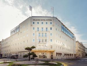 ein großes weißes Gebäude mit zwei Flaggen darüber in der Unterkunft IMLAUER HOTEL PITTER Salzburg in Salzburg