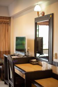 a room with a desk with a mirror and a television at Ariya inn Chiangrai in Chiang Rai