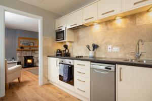 een keuken met witte kasten en een fornuis met oven bij Highland Holiday Cottages in Newtonmore