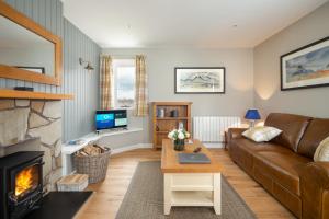 een woonkamer met een bank en een open haard bij Highland Holiday Cottages in Newtonmore