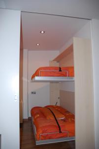 Zimmer mit 2 Etagenbetten mit orangefarbener Bettwäsche in der Unterkunft Cal Miquel in Alpens