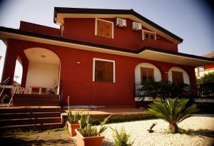 een groot rood huis met een veranda en een trap bij B&B Casalotto Inn in Aci SantʼAntonio