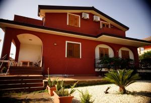 Una gran casa roja con porche y escaleras. en B&B Casalotto Inn, en Aci SantʼAntonio