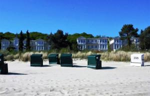 a row of green beach chairs sitting in the sand at Duene25 in Zinnowitz