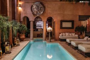 a large swimming pool in a room with couches at Riad Noir d'Ivoire in Marrakesh