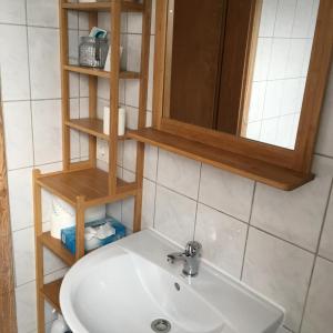 ein weißes Waschbecken im Bad mit Holzregalen in der Unterkunft Augsburg-Bergheim E. in Augsburg